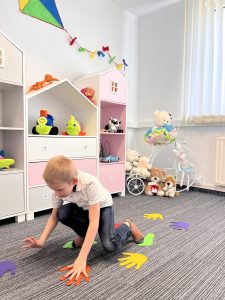 Chłopiec wykonujący ćwiczenia ruchowe w gabinecie Akademii LOOK w Katowicach podczas terapii ręki, w kolorowym wnętrzu pełnym zabawek